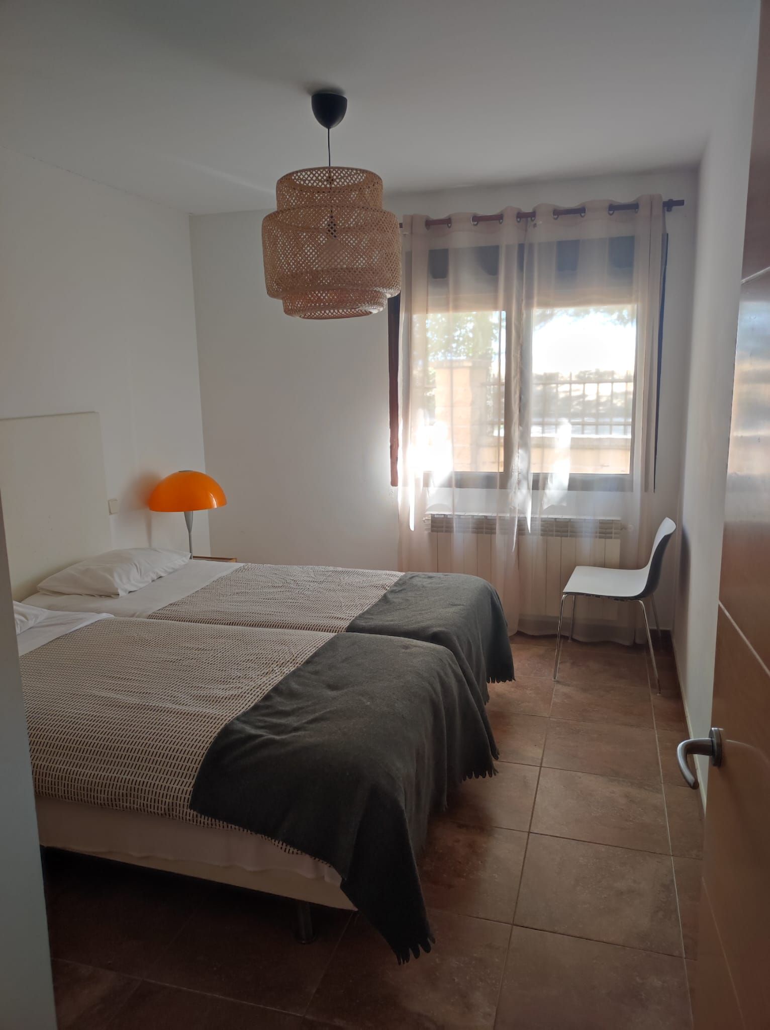 Een slaapkamer met een bed, een bureau en een stoel.