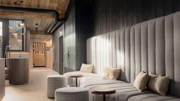 A modern interior with a sofa, ottomans, and a wooden ceiling.