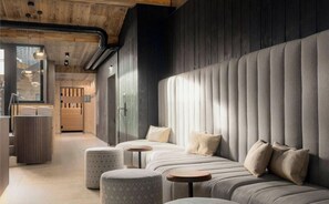 Een modern interieur met een bank, poefs en een houten plafond.