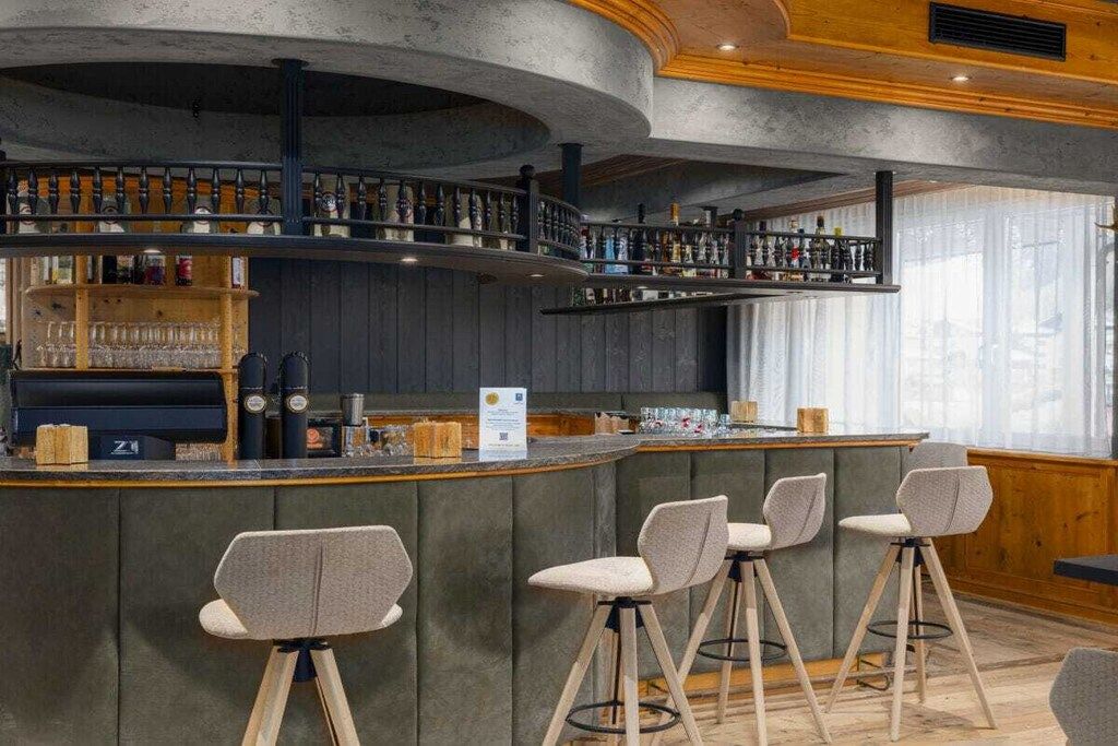 A bar area with stools, a counter, and shelves with bottles.