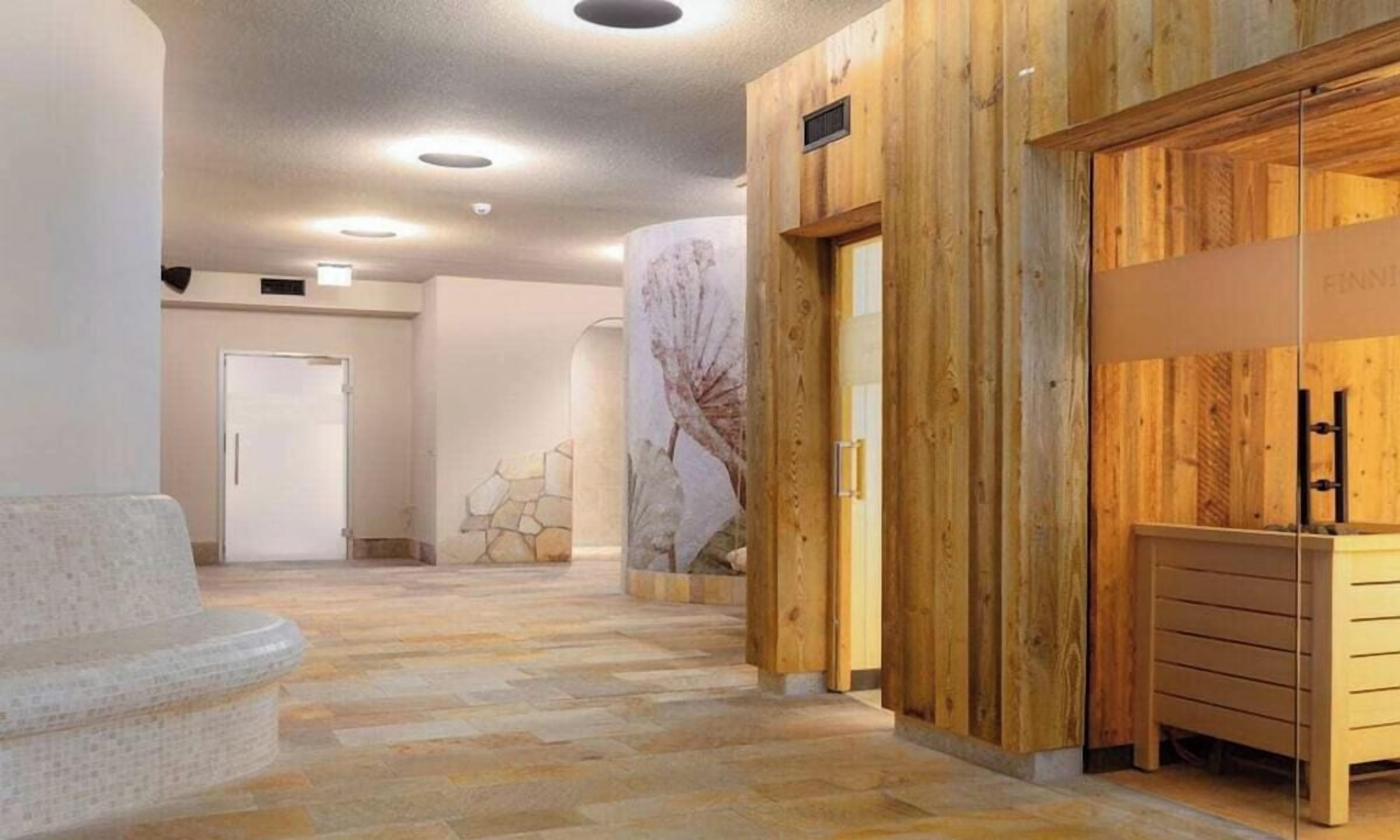 Un hall d’hôtel avec un sol en pierre, des murs en bois, un comptoir d’accueil et une porte au fond.