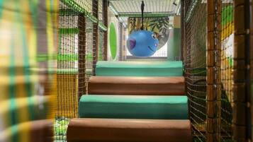 A multi-level indoor play area with netted walls and a central climbing structure.