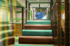 Een meerlaags binnenspeelgebied met gaaswanden en een klimconstructie in het midden.