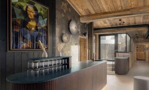 Un intérieur moderne avec un espace bar, un plafond en bois et un grand tableau au mur.