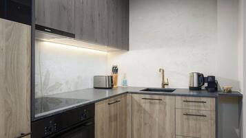 Een moderne keuken met houten kastjes, een inbouwoven en een roestvrijstalen broodrooster.