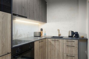 Een moderne keuken met houten kastjes, een inbouwoven en een roestvrijstalen broodrooster.