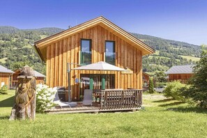 A wooden cabin with a balcony, surrounded by a grassy area and trees. - Cabin with 1 bedroom (St. Georgen am Kreischberg)