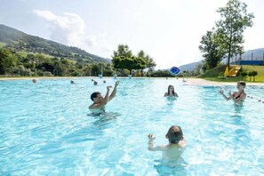 A swimming pool with multiple people in the water, surrounded by trees and hills in the background. - Cabin with 1 bedroom (St. Georgen am Kreischberg)