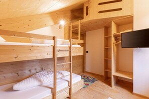A bunk bed room with wooden walls and a television.