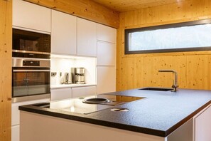 A modern kitchen with built-in appliances, a window, and a sink.