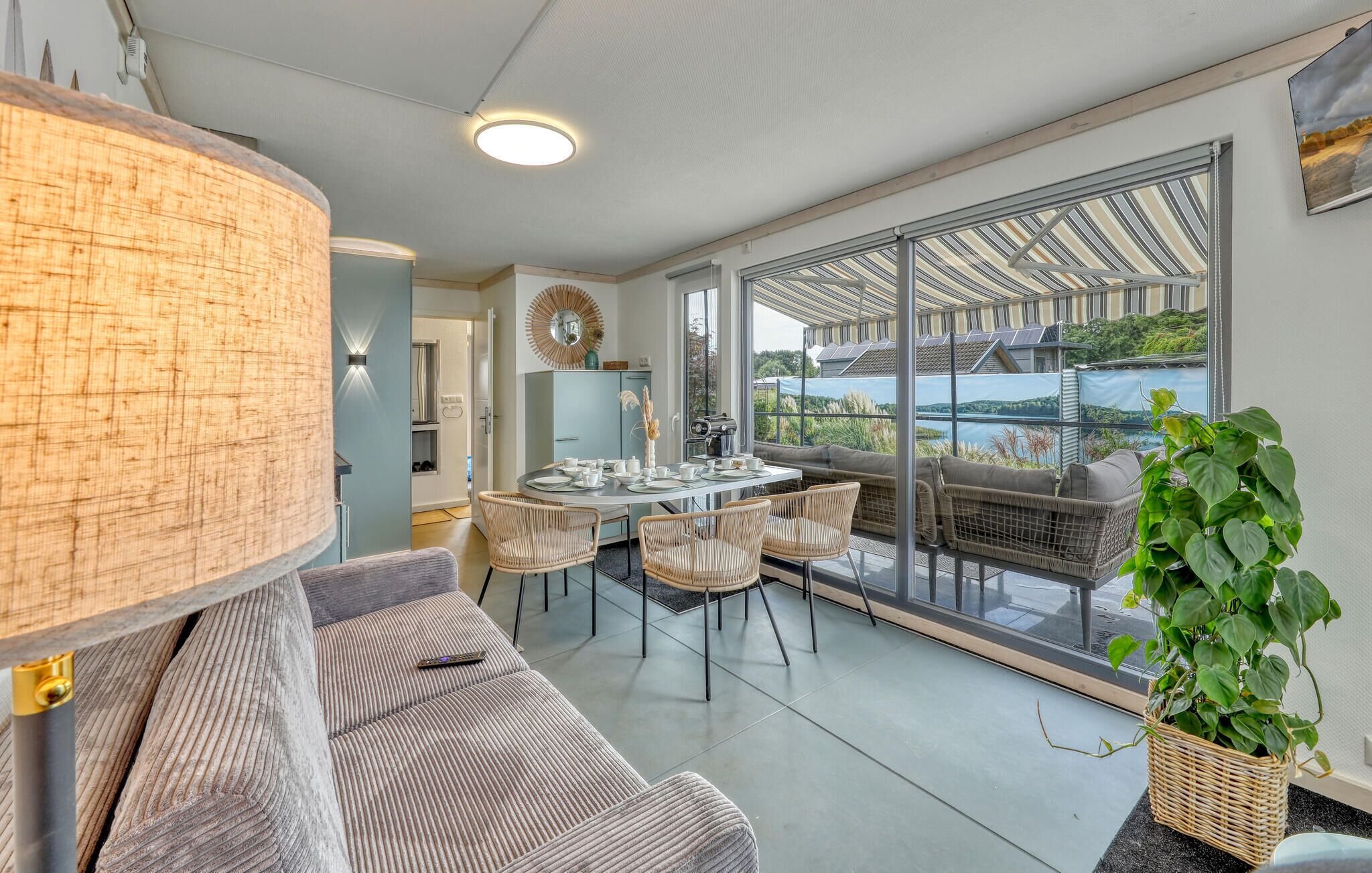 Una sala de estar moderna con comedor, ventanas amplias y vista a un lago.