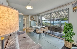 Een moderne woonkamer met een eetgedeelte, grote ramen en uitzicht op een meer.