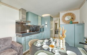 A modern kitchen with a dining area, featuring a Bosch oven, light blue cabinets, and a decorative wall piece.