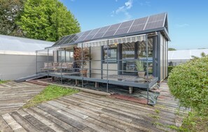 A modern house with a solar panel roof, a covered patio with outdoor furniture, and a wooden deck. - 1 bedroom awesome home in Otterndorf (Otterndorf)