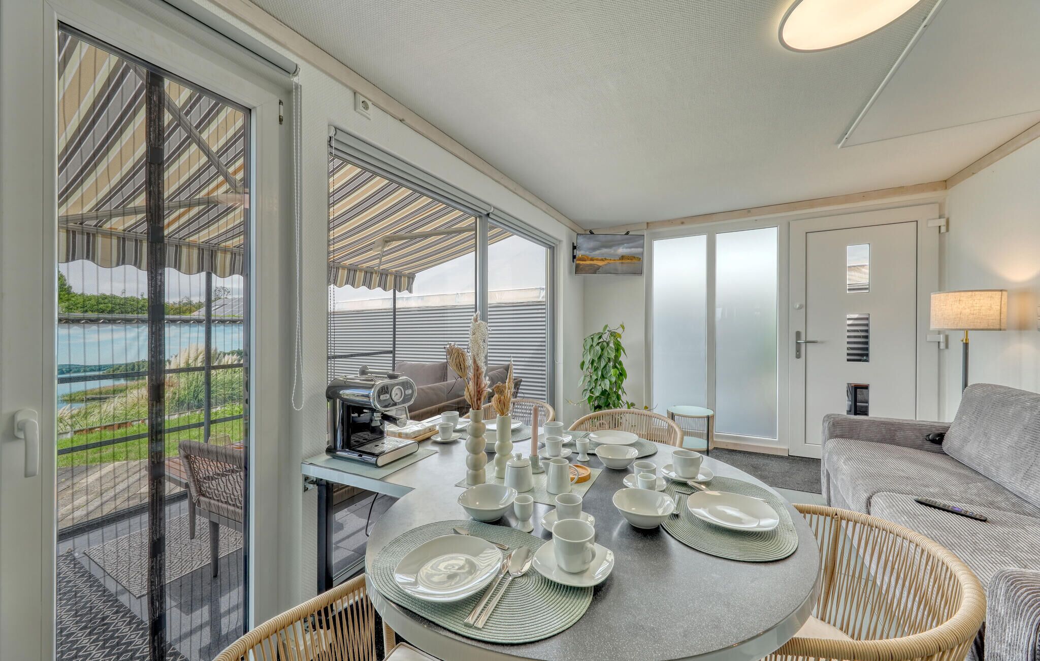A dining area with a round table set for four, surrounded by wicker chairs.