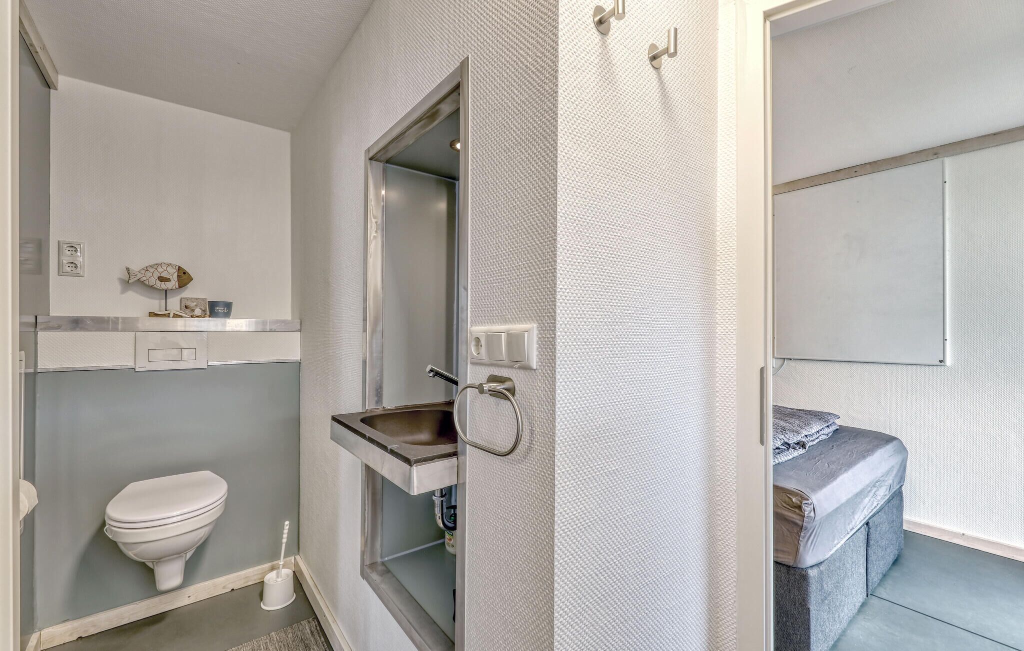 A bathroom with a toilet, a sink, and a mirror.