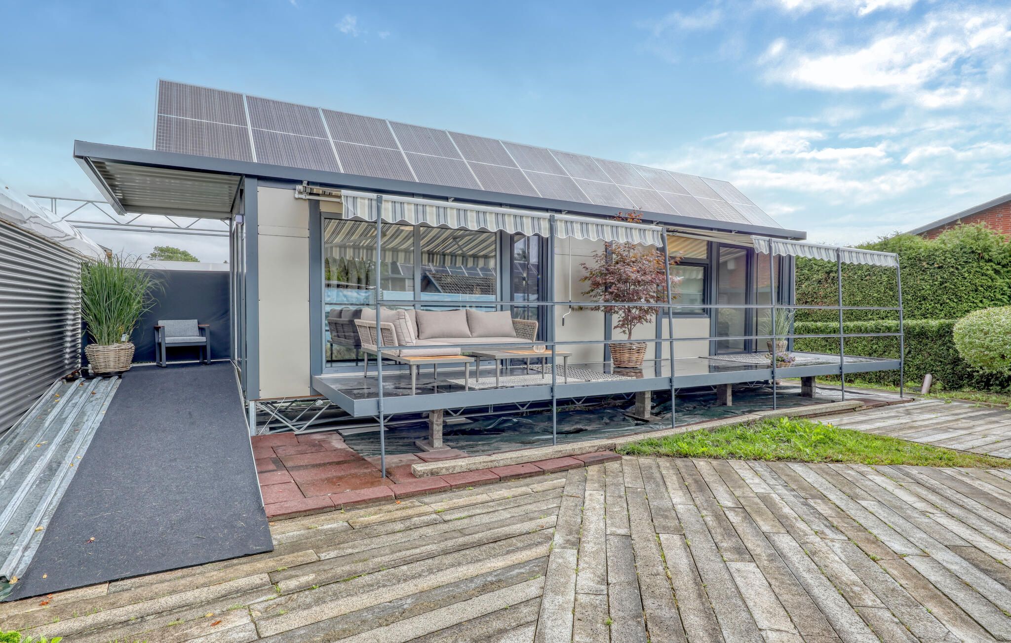 Une maison moderne dotée d’un patio couvert, de panneaux solaires et d’un jardin.
