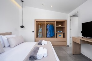 Ein modernes Hotelzimmer mit Bett, Kleiderschrank, Schreibtisch und Fernseher.