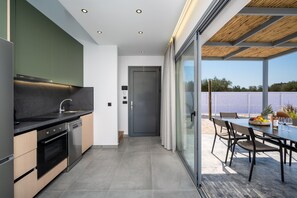 Eine moderne Küche mit integriertem Backofen, Geschirrspüler und einem Essbereich mit Tisch und Stühlen.