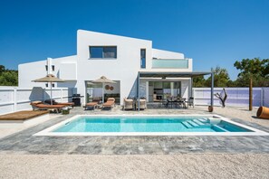 A modern two-story house with a swimming pool, outdoor seating, and a covered patio area. - Villa located in Kolympia (Rhodes)