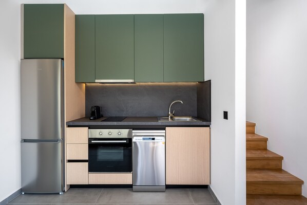 A compact kitchen with a built-in dishwasher, oven, and a stainless steel refrigerator. - Villa located in Kolympia (Rhodes)