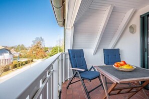 A balcony with two chairs and a table, a clear view of the surrounding area, and a tiled floor. - Störtebekerstraße 9 - Apartment 6 (Zingst (Ostseeheilbad))