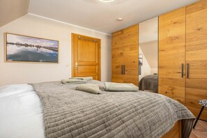 A bedroom with a bed, a wooden wardrobe, a door, and a framed picture on the wall. - Störtebekerstraße 9 - Apartment 6 (Zingst (Ostseeheilbad))