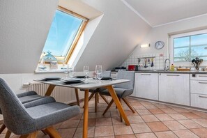 Eine moderne Küche mit Essbereich, ausgestattet mit einem für vier Personen gedecktem Tisch, einem Fenster mit Blick und einer Uhr an der Wand.