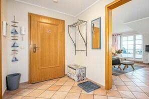 A hallway with a wooden door, a metal drying rack, a small chest of drawers, and a tiled floor. - Störtebekerstraße 9 - Apartment 6 (Zingst (Ostseeheilbad))