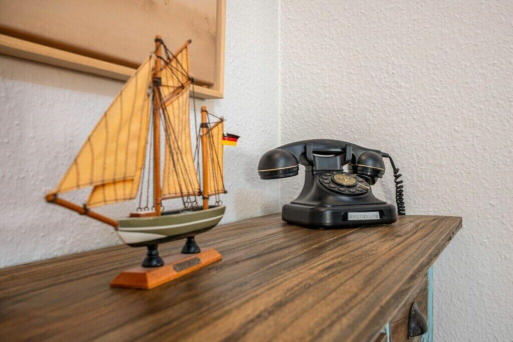 A wooden table with a model sailboat and an old-fashioned rotary dial telephone.