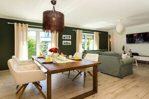 Ein modernes Wohnzimmer mit Esstisch, Sofa und großem Fenster.