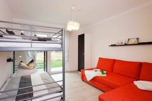 Ein Zimmer mit einem Etagenbett, einem roten Sofa, einer Pendelleuchte und einer Tür, die nach draußen führt.