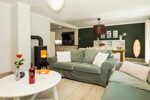 A modern living room with a green sofa, a white table, and a fireplace. - Haus Frieda in Karlshagen (Karlshagen (Ostseebad))