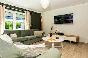 Ein modernes Wohnzimmer mit einem grünen Sofa, einem weißen Couchtisch und einer Holzbank.