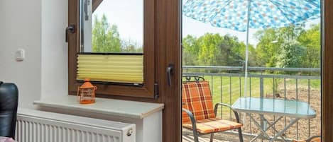 Una habitación con ventana, un radiador, una silla, una mesa y un paraguas.