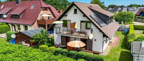 En bostadsfastighet med ett sluttande tak, en balkong med räcke och en satellitmottagare.