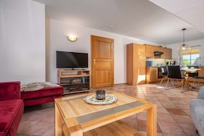 Ein modernes Wohnzimmer mit einem roten Sofa, einem Holztisch und einem Fernseher.