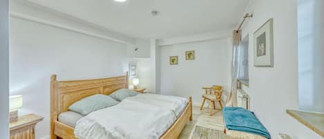 A bedroom with a wooden bed, a bedside table, a chair, and a radiator.