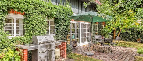 A patio area with a grill, outdoor furniture, and a covered seating area.