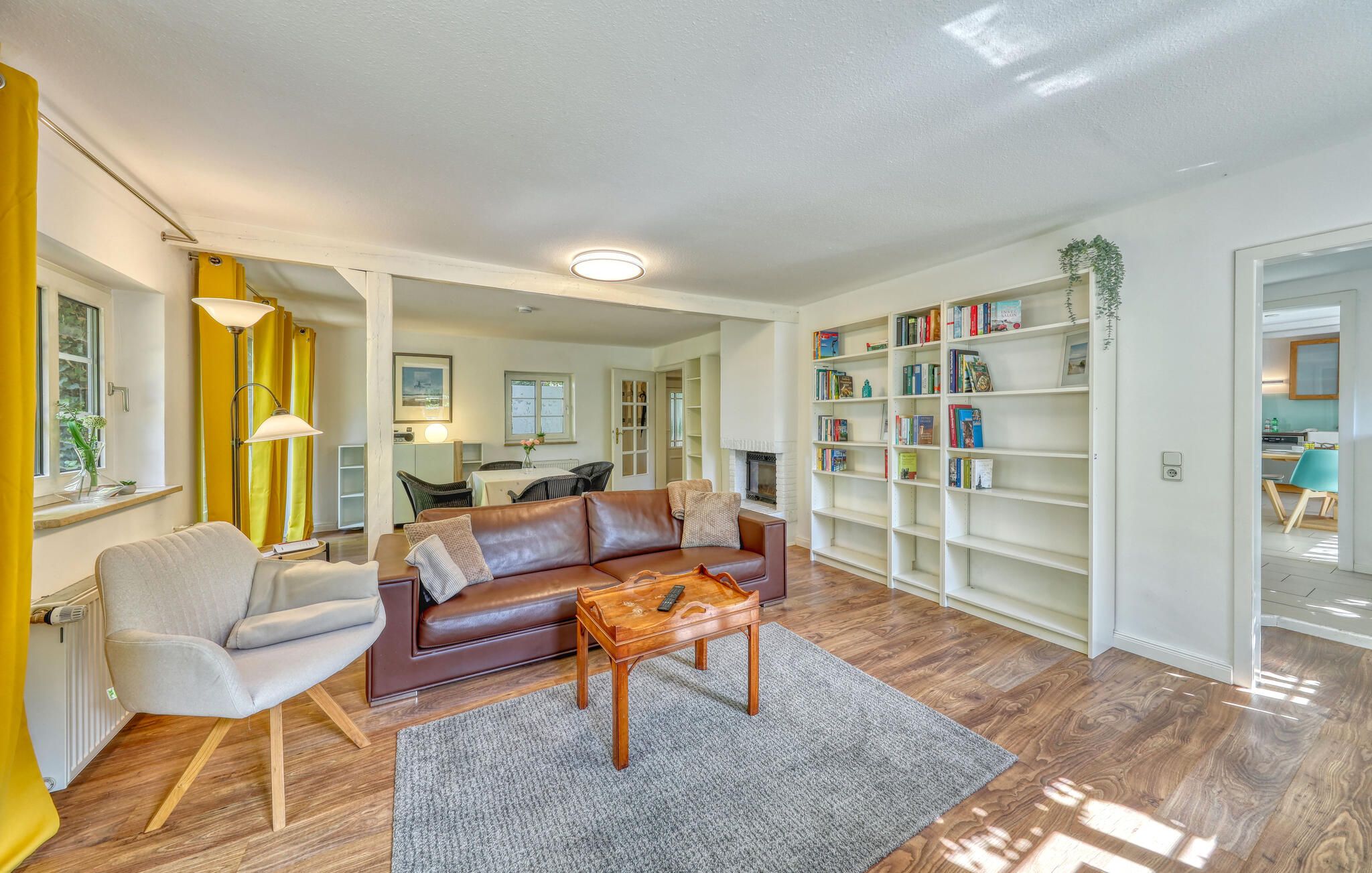 Una sala de estar con un sofá de cuero marrón, una mesa de centro de madera y una estantería llena de libros.