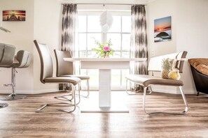 A modern dining area with a white table, two chairs, and a vase with flowers. - Holiday home with 2 bedrooms (Fuhlendorf)