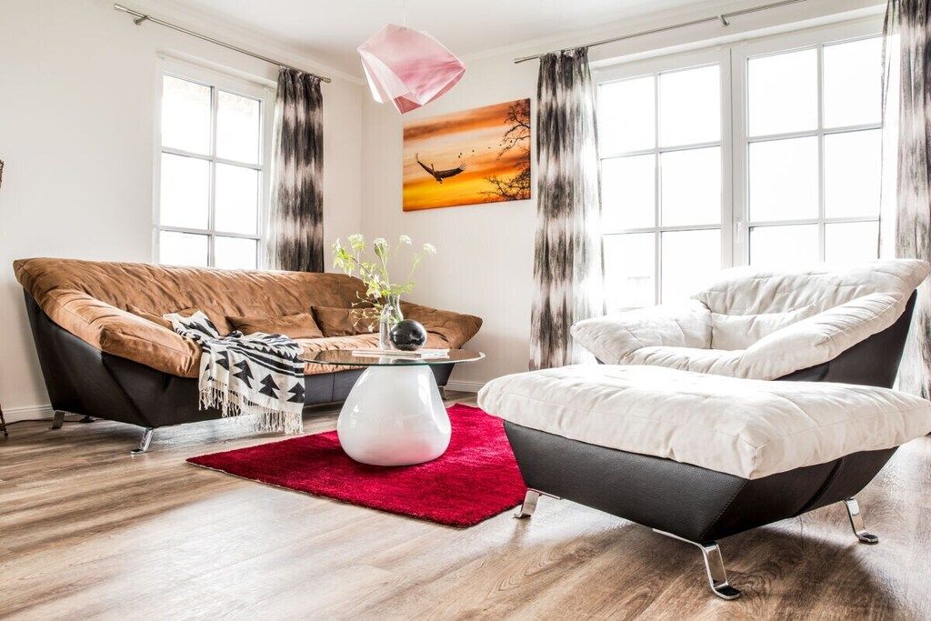 Un salon moderne avec un canapé, un fauteuil et une table basse agrémentée d’un vase.