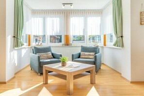 A room with two armchairs, a wooden coffee table, and a view through large windows. - Holiday apartment with 1 bedroom (Ahlbeck (Seebad))