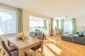 A modern living room with a dining area, a sofa, and a kitchen in the background. - Holiday apartment with 1 bedroom (Ahlbeck (Seebad))