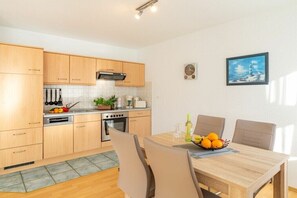 Une cuisine moderne avec des meubles en bois, une table à manger avec des chaises et un tableau accroché au mur.