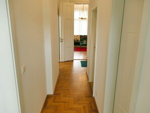 Ein Korridor mit Holzboden, der zu einem Raum mit einer Couch und einem Tisch führt.