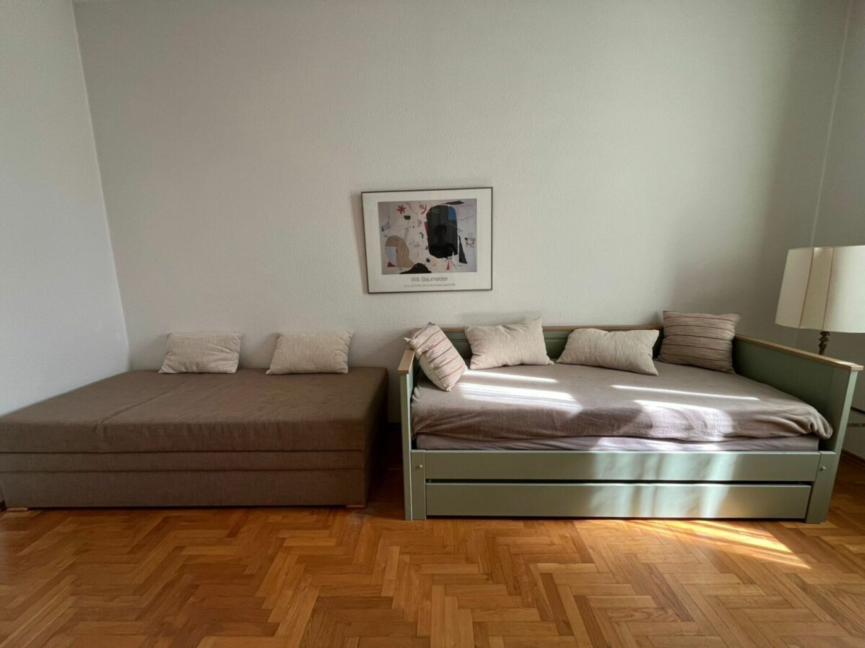 Une pièce comprenant un lit, un canapé, une lampe et un tableau encadré accroché au mur.
