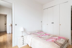 Un dormitorio con una cama, una mesita de noche, una lámpara y un armario.