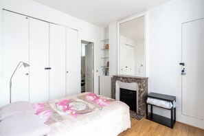 A bedroom with a bed, a fireplace, a mirror, and a wardrobe. - Cozy 1BDR Apartment for 4 Near Champs-Elysees (Paris)