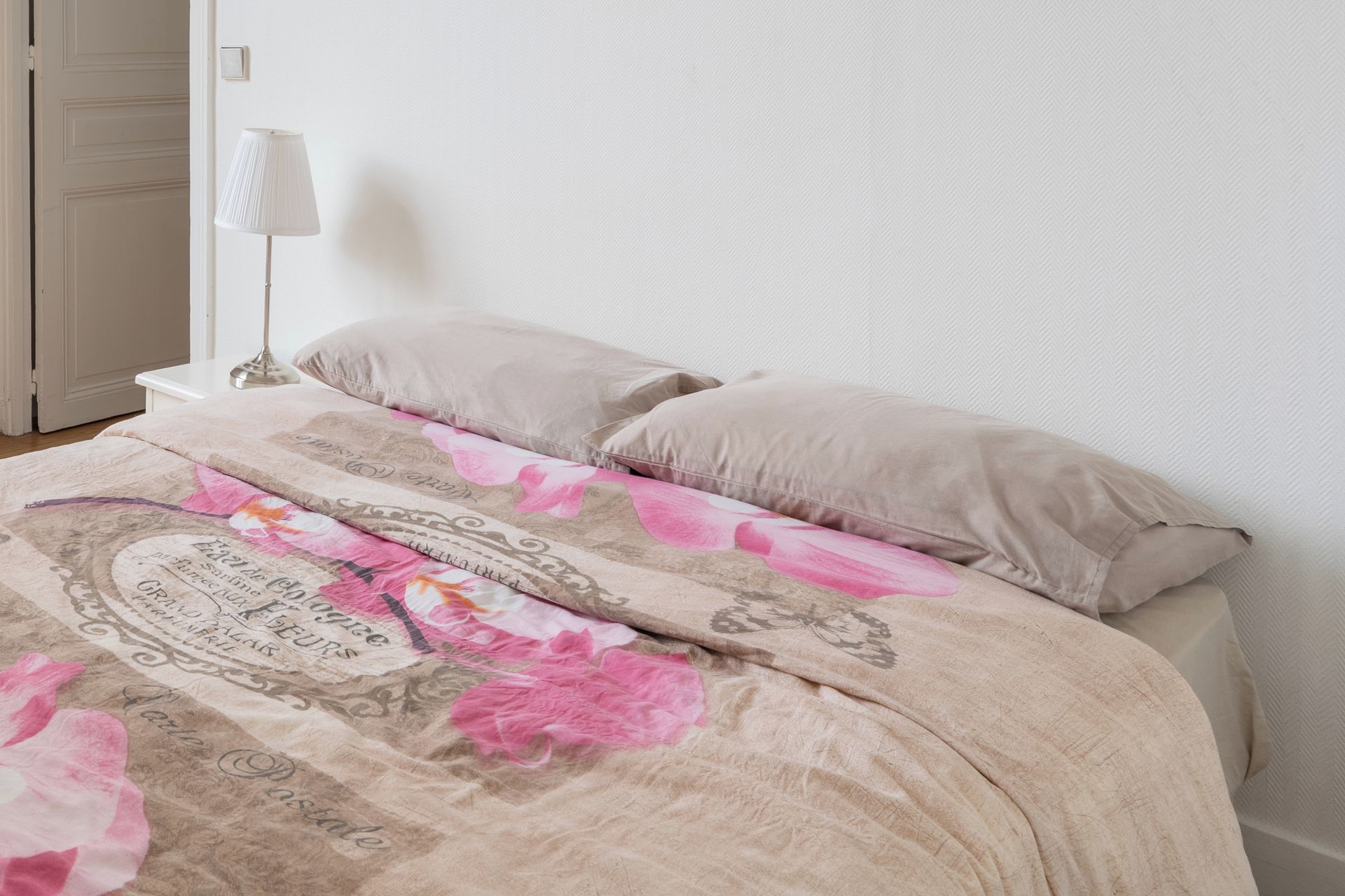 A bed with a floral patterned bedspread and two pillows.